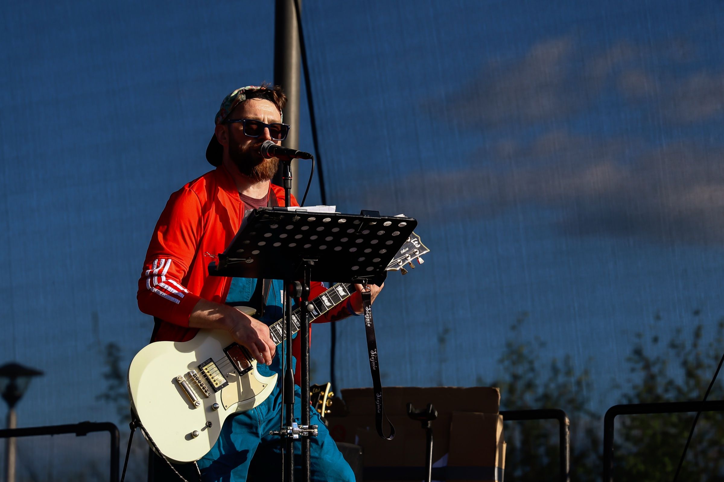 Gitarzysta Bigiel Band śpiewa na scenie plenerowej w popołudniowym słońcu