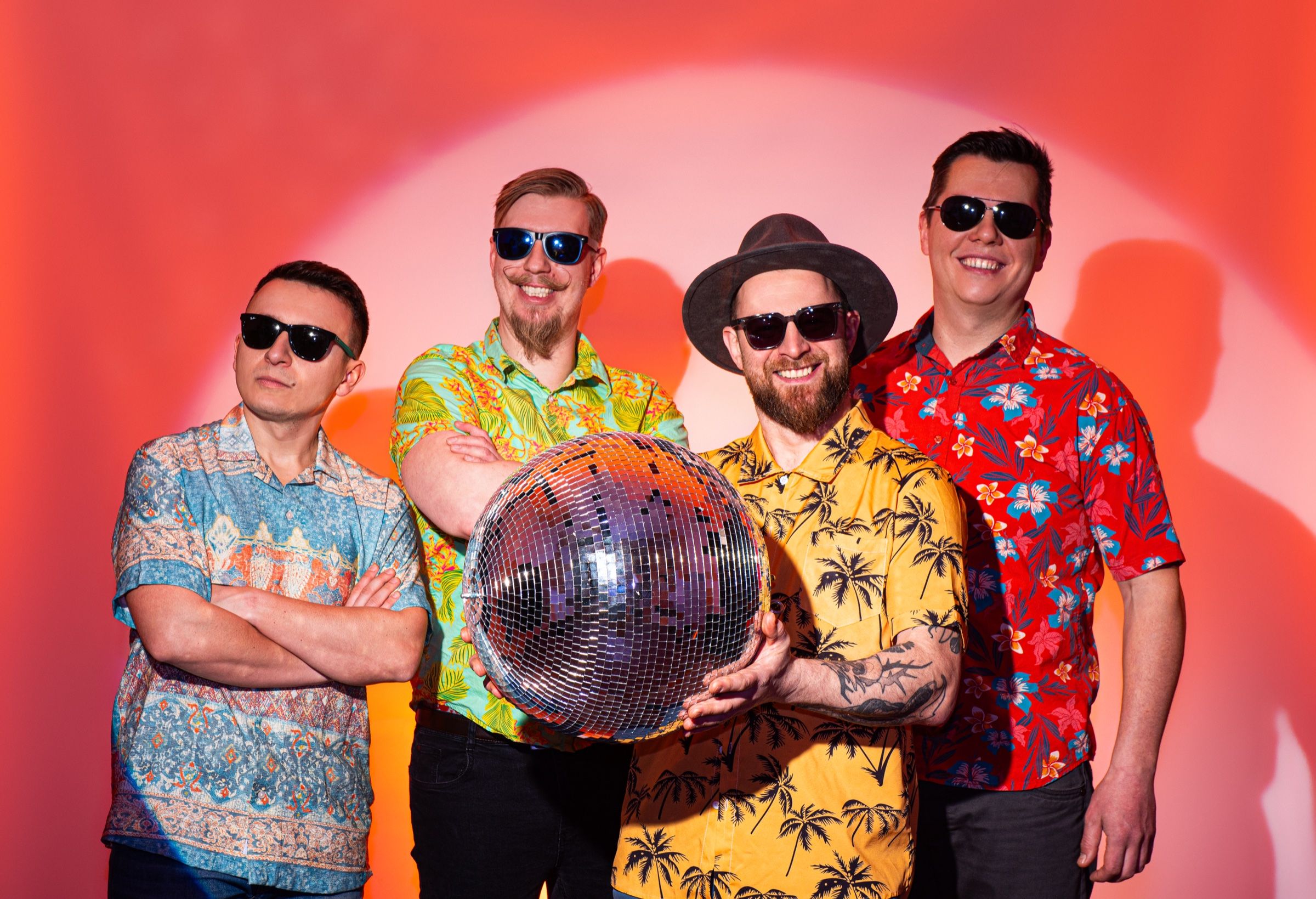 Czterech muzyków Bigiel Band z kulą dyskotekową na czerwonym tle